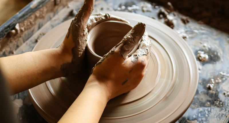 Teacher shaping pottery on a wheel to sell as a creative side hustle